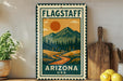 A vintage-style metal sign with a mountain landscape and a sun in the sky, featuring the text "FLAGSTAFF ARIZONA USA" in the center.