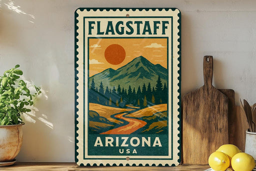 A vintage-style metal sign with a mountain landscape and a sun in the sky, featuring the text "FLAGSTAFF ARIZONA USA" in the center.