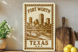 a decorative metal sign with a cityscape and a bridge, placed on a shelf next to a wooden cutting board and some potted plants.