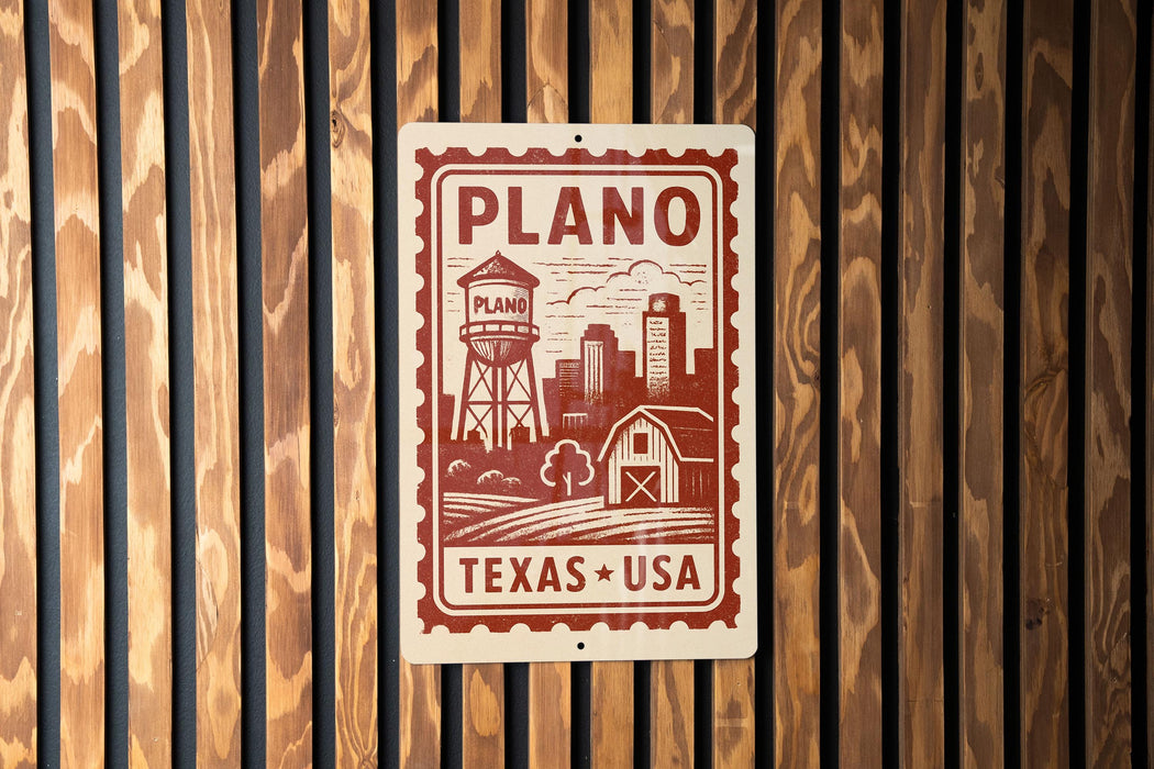 A sign with the text "PLANO TEXAS USA" and an illustration of a water tower, barn, and field, mounted on a wooden wall.