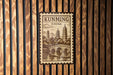 a wooden wall with a decorative sign that reads "KUNMING CHINA" and depicts a traditional Chinese temple with pagodas.