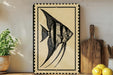 a framed illustration of a fish, specifically an angelfish, on a wooden surface.