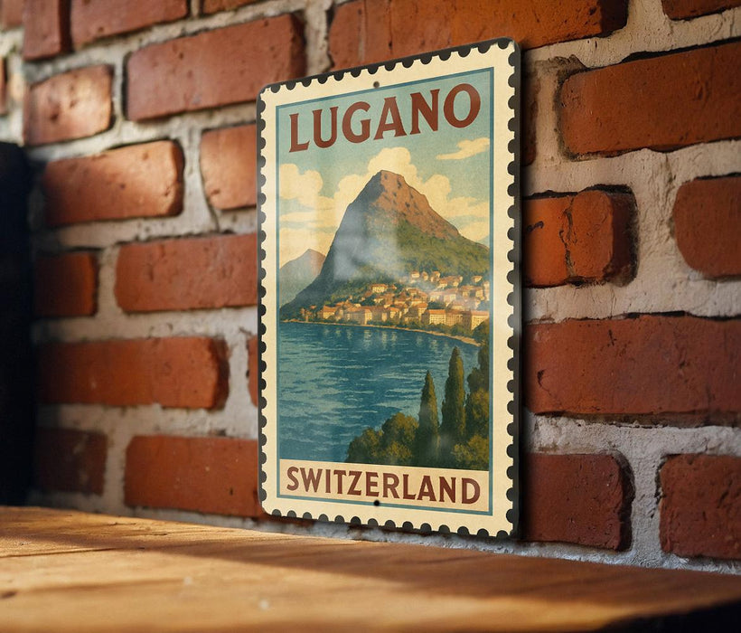 A vintage-style postage stamp depicting a scenic view of Lugano, Switzerland, with a mountain and a town in the background.