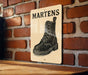 A sign with the word "MARTENS" written on it, featuring a black and white illustration of a leather boot.