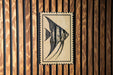 a wooden wall with a framed picture of a fish, which appears to be a decorative piece.