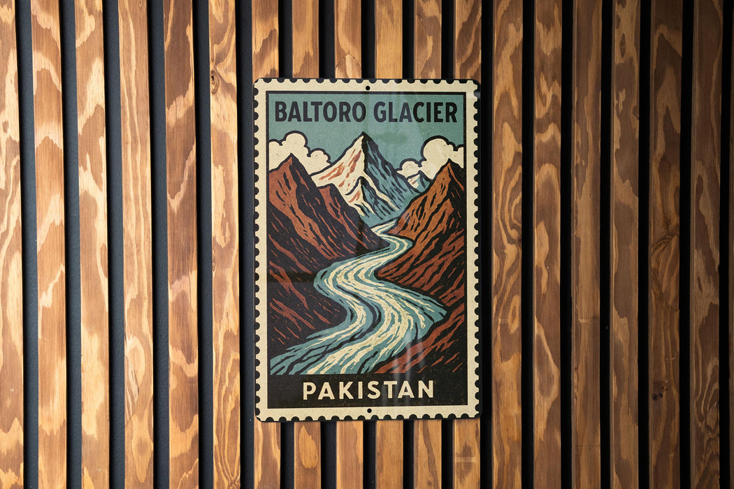 A vintage postage stamp featuring a mountain landscape with a river, mounted on a wooden wall.