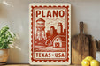 A vintage-style sign for Plano, Texas, featuring a water tower and a barn, with the text "PLANO TEXAS USA" printed on it.