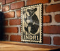 A metal sign featuring a black and white illustration of a koala bear is mounted on a brick wall.