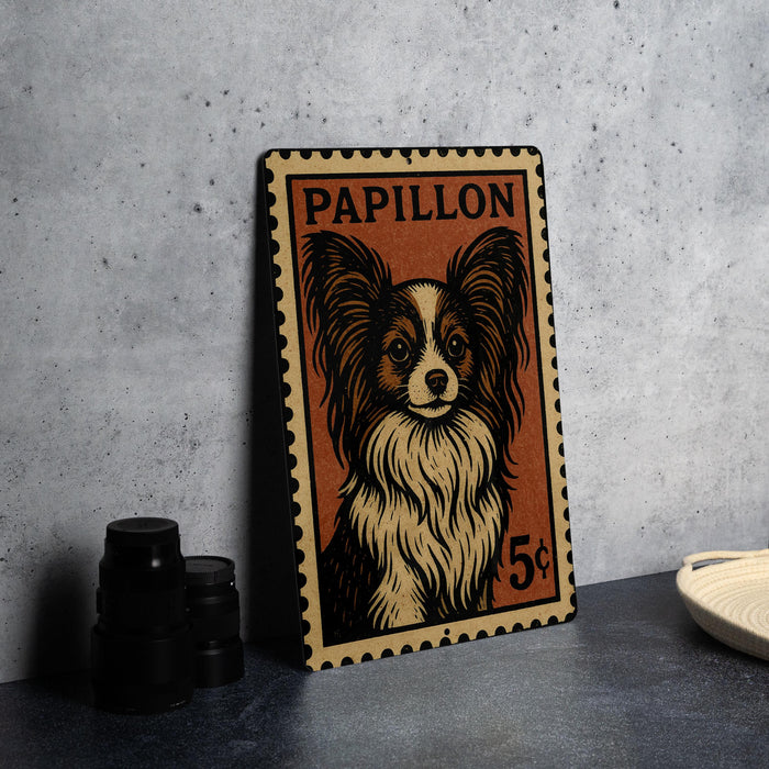A metal stamp featuring a Papillon dog, with a price of 5 cents, is displayed on a table next to some black camera lenses.