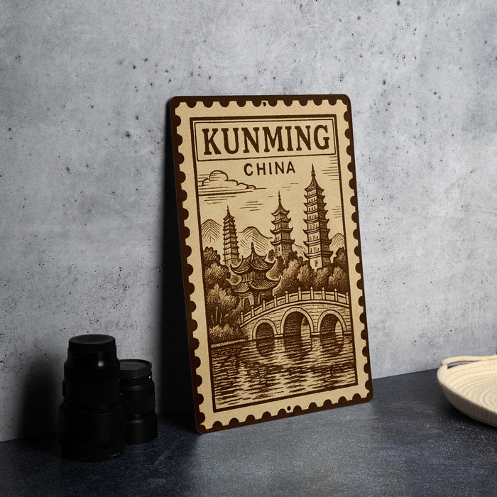 A wooden sign with a decorative border and an illustration of pagodas and a bridge, representing Kunming, China.