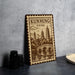 A wooden sign with a decorative border and an illustration of pagodas and a bridge, representing Kunming, China.