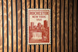 A postage stamp featuring the cityscape of Rochester, New York, USA, with a waterfall in the background.