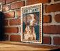 A metal sign featuring a portrait of a dog with the name "BRITTANY" on it, mounted on a brick wall.