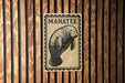 A sign with the word "MANATEE" printed on it, depicting a manatee.