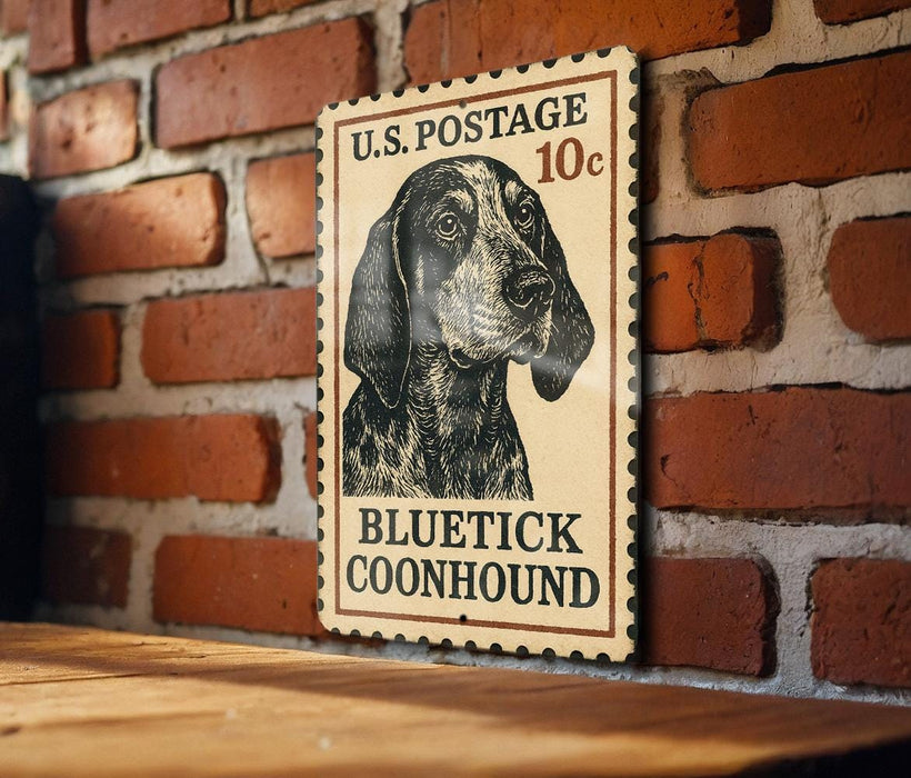 A vintage-style postage stamp featuring a blue and black dog, likely a Blueetick Coonhound, mounted on a brick wall.