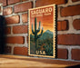 A vintage-style poster of Saguaro National Park, featuring a cactus and desert landscape, is displayed on a brick wall.