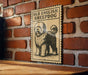 a sign with a picture of a sheepdog, mounted on a brick wall.