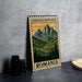A metal sign with a mountain landscape and pine trees, featuring the text "CARPATHIAN MOUNTAINS ROMANIA" on it, is displayed on a table next to some black camera lenses.