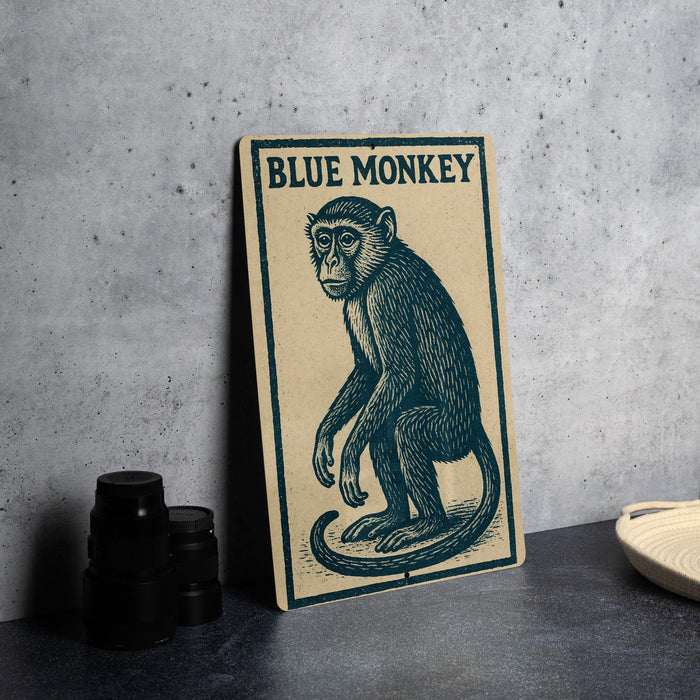 A framed illustration of a blue monkey is displayed on a wall, accompanied by a stack of black camera lenses and a woven basket.