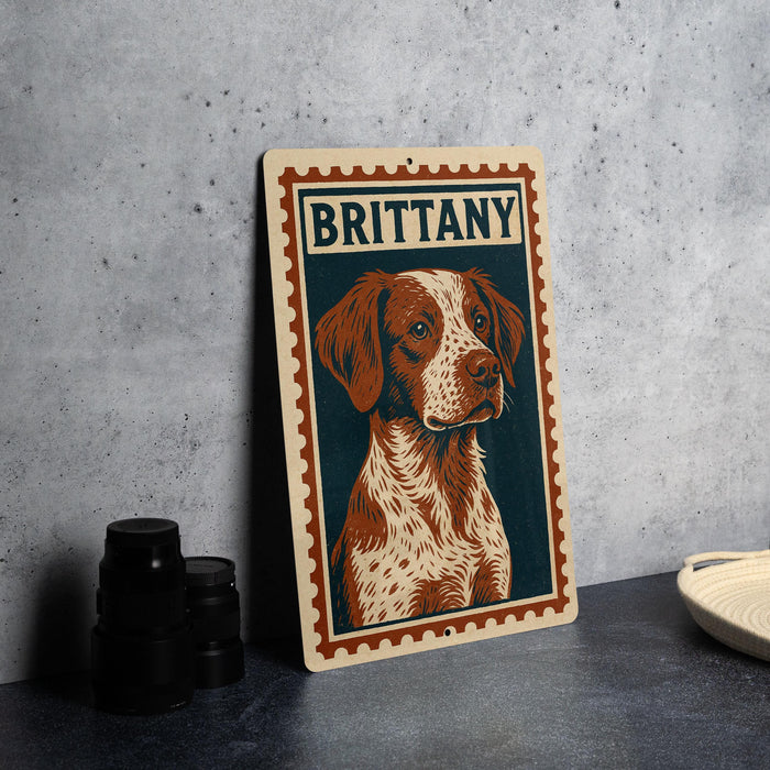 A metal sign featuring a portrait of a dog with the name "BRITTANY" on it, placed on a countertop next to some black camera lenses.