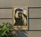 A metal plaque featuring a close-up of a colobus monkey, with a postage stamp-like design.