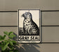 a sign with a black and white illustration of a seal, mounted on a wall.
