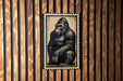 A metal sign featuring a black and white illustration of a gorilla is mounted on a wooden wall.