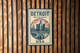 A metal sign with the text "DETROIT MICHIGAN USA" and an illustration of a city skyline.