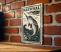 A vintage-style postage stamp featuring a narwhal, a type of whale, is displayed on a brick wall.