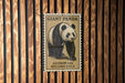 A framed image of a panda bear is displayed on a wooden wall.