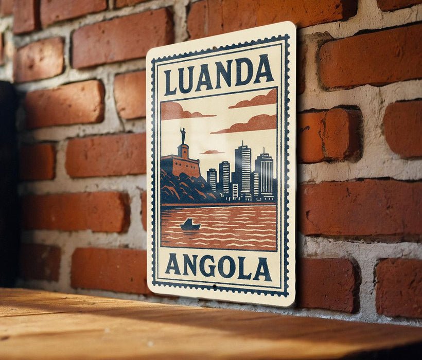 A metal sign with the text "LUANDA ANGOLA" and an illustration of a cityscape with a river and a boat.