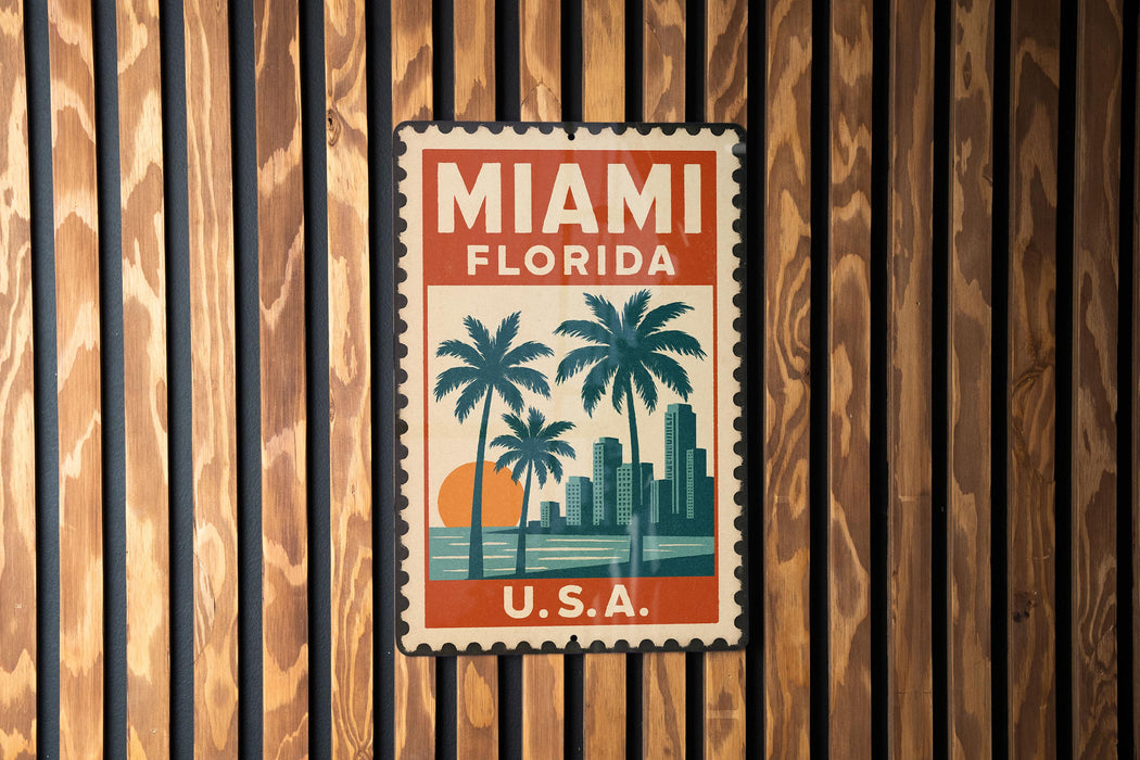 A vintage-style stamp or sign with the text "MIAMI FLORIDA" and a graphic of palm trees and a sunset, mounted on a wooden wall.