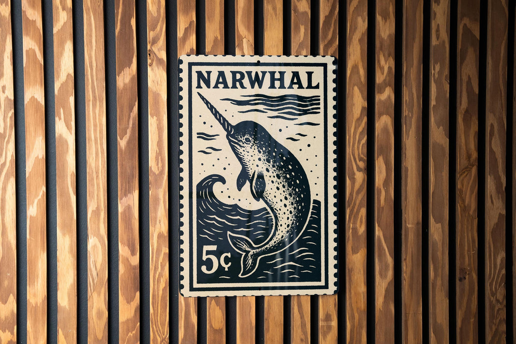 A black and white postage stamp featuring a narwhal, a type of whale, is displayed on a wooden wall.