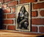 A framed image of a gorilla is displayed on a brick wall.