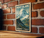 A vintage-style poster of a mountain landscape with the text "MONT BLANC FRANCE ITALY" displayed on a brick wall.