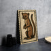 a wooden frame with a cartoon illustration of a brown animal, possibly a cat or a small rodent, on a black background.