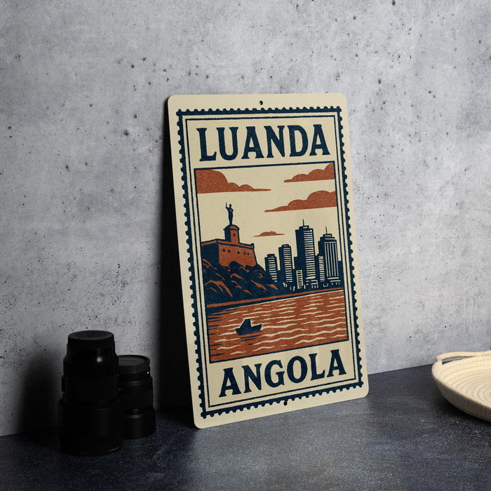 a poster or sign with the text "LUANDA ANGOLA" and an illustration of a cityscape with a river and a boat.
