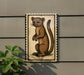 a brown cartoon-style animal, possibly a cat or a small rodent, standing on its hind legs and looking up.