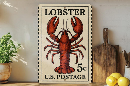 A vintage-style stamp featuring a lobster, with the text "LOBSTER 5c U.S. POSTAGE" printed on it. The stamp is displayed on a shelf next to a wooden cutting board and some kitchen utensils.