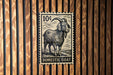 A black and white stamp depicting a domestic goat, with the text "DOMESTIC GOAT" printed on it.