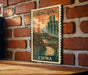 A vintage postage stamp depicting a cityscape with a bridge, hanging on a brick wall.