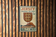 A Jersey Channel Islands postage stamp is displayed on a wooden wall.
