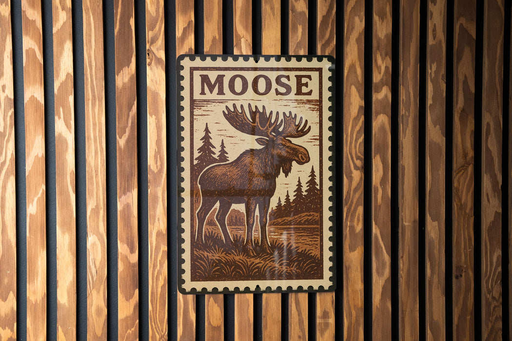 A framed image of a moose is displayed on a wooden wall.