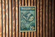 A green and white postage stamp featuring a fish is displayed on a wooden wall.