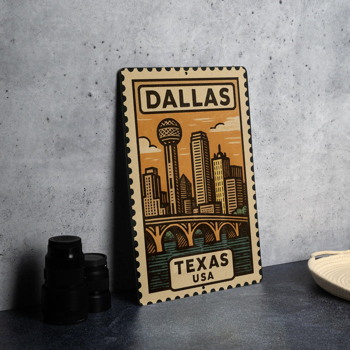A metal sign with a stylized illustration of the Dallas skyline and the text "DALLAS TEXAS USA" is displayed on a table.