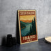 A metal sign with a vintage-style illustration of a scenic landscape, featuring a river, mountains, and pine trees, is displayed on a gray countertop.