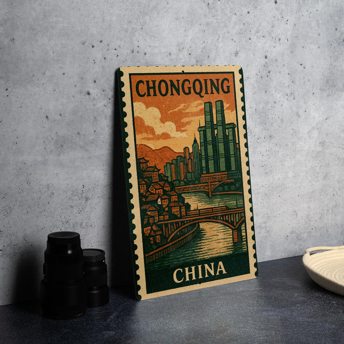 A vintage postage stamp depicting a cityscape with a bridge, surrounded by mountains, is displayed on a table.