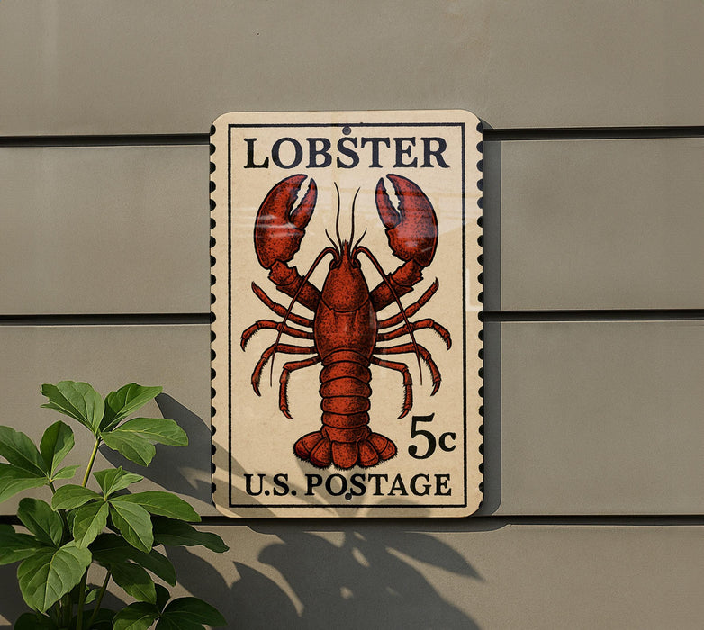 A lobster postage stamp is displayed on a wall, with a plant to the left.