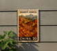 A postage stamp-like sign with a mountain landscape and the text "Zhangye Dania" on it, mounted on a wall.