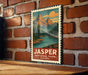 A vintage-style poster of a mountain landscape with a river, hanging on a brick wall.